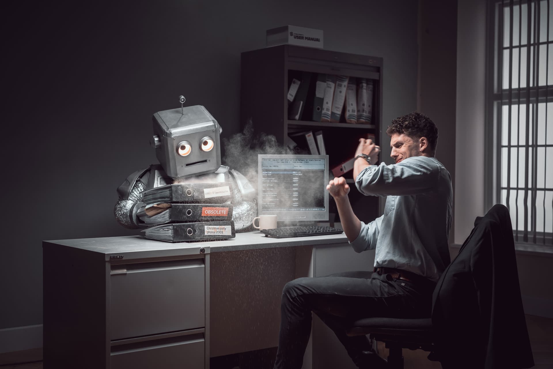 Tristan Alexander in an office with a robot, fists raised in a comedic commercial scene