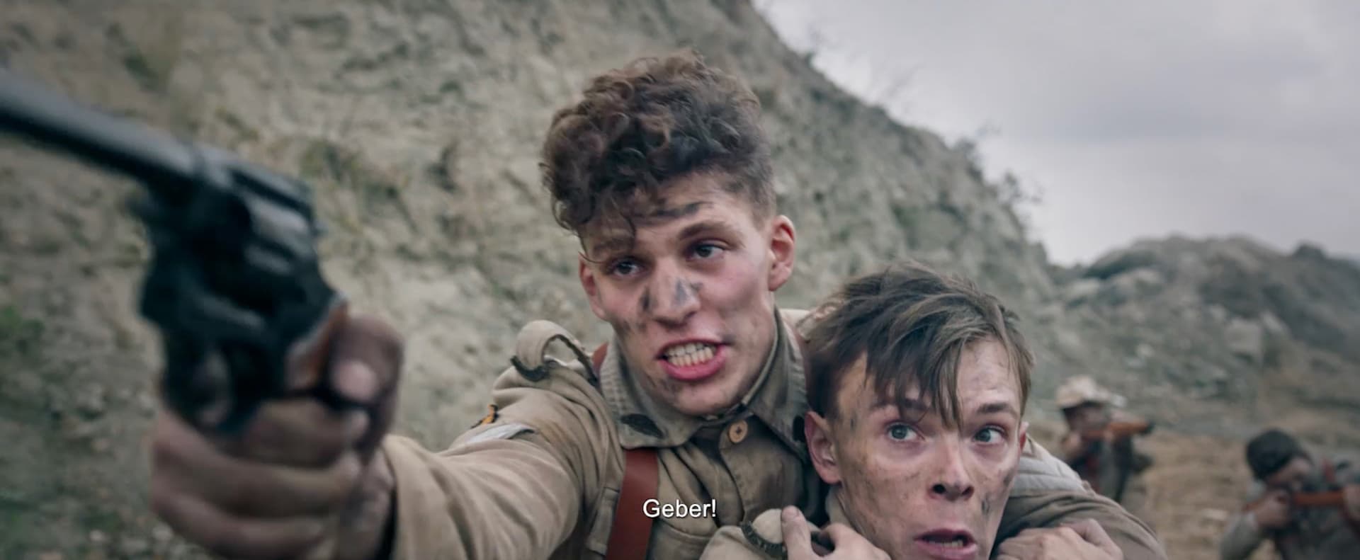 Tristan Alexander pointing a revolver while protecting a fellow soldier in an intense war scene