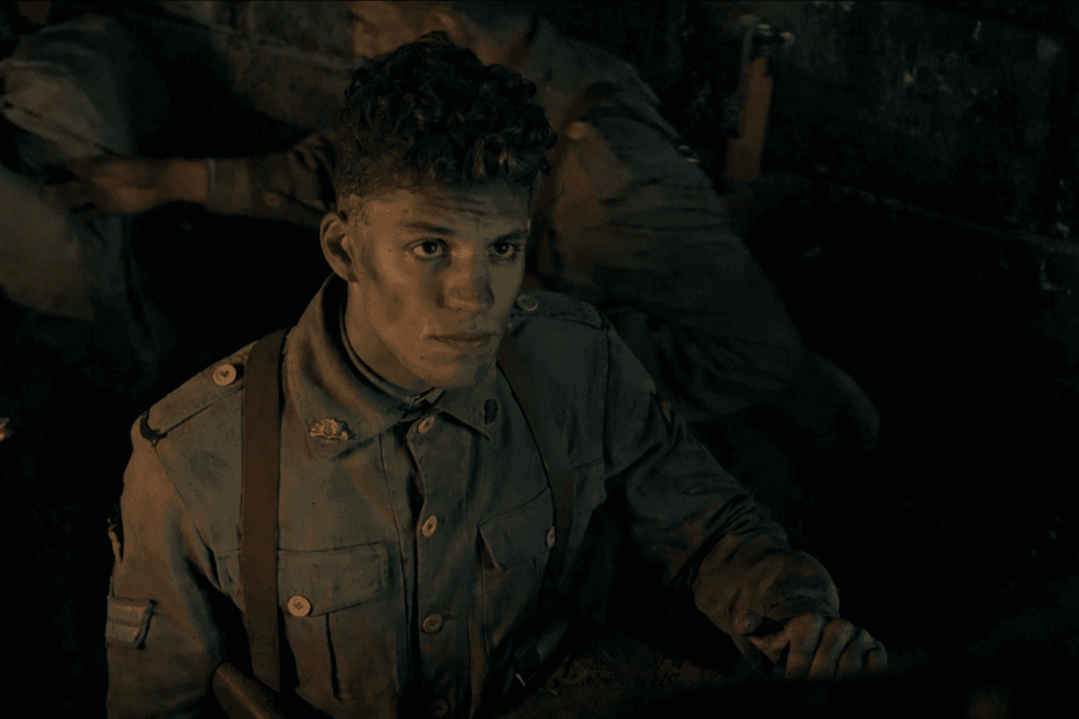 Tristan Alexander in WWI uniform in a dark trench scene, looking up intensely