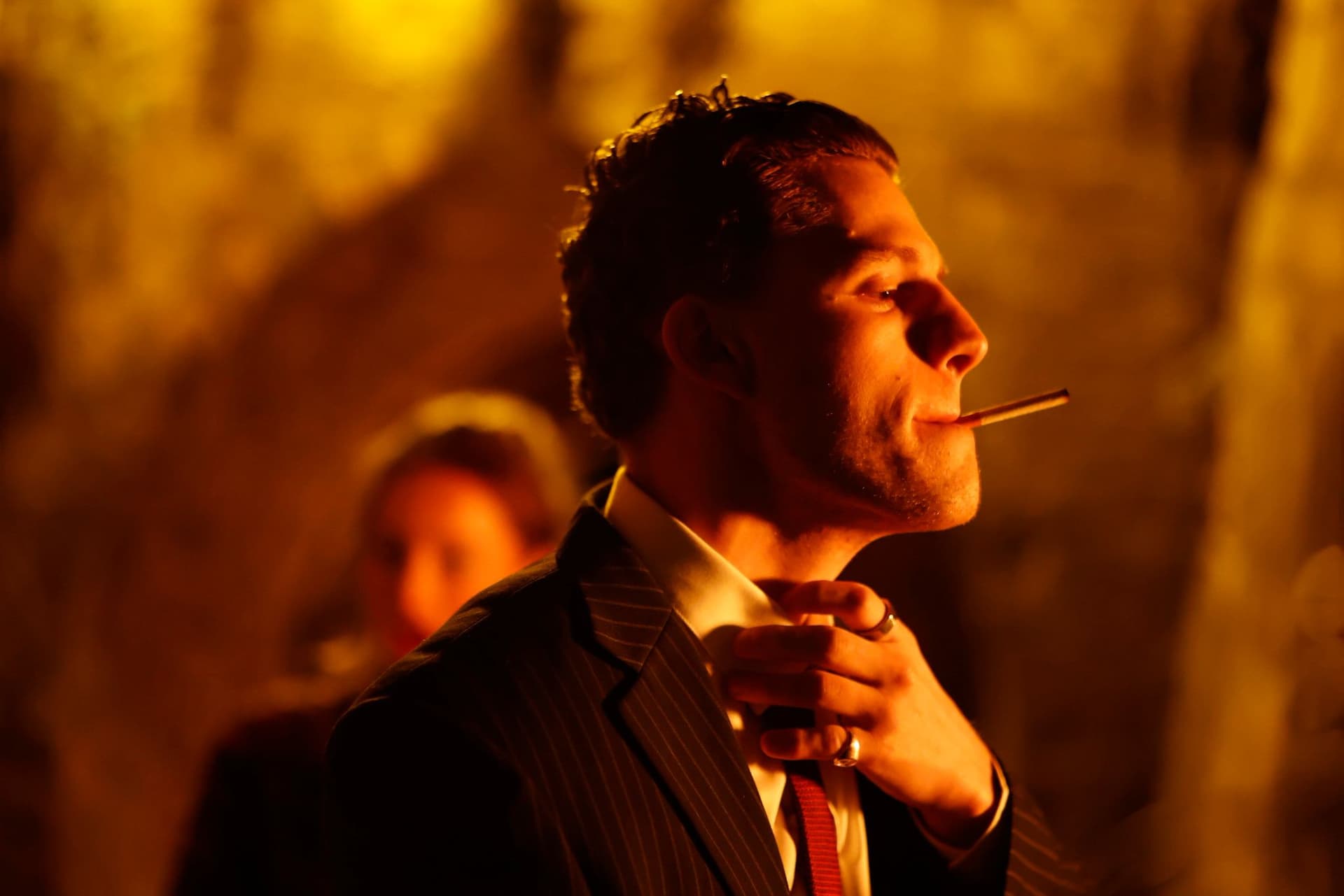 Tristan Alexander in profile with cigarette, dramatic amber lighting