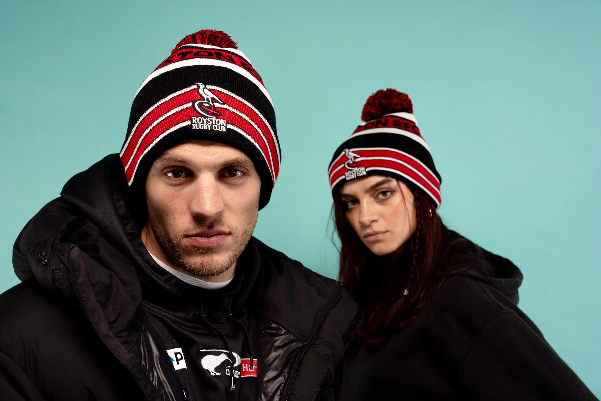 Tristan Alexander and co-model wearing Royston Rugby Club beanies against a teal backdrop